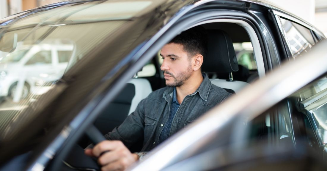A man seated in the driver's seat of a car.