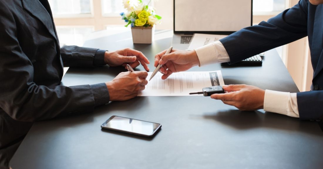 Two people engaged in signing documents at a table.