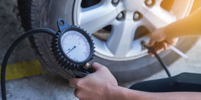 A person checking tyre pressure with a gauge, ensuring optimal inflation for vehicle safety and performance.