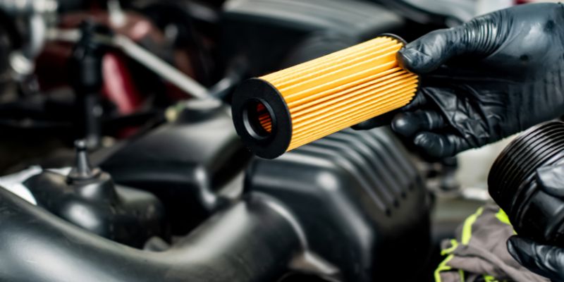 A person wearing black gloves is holding a yellow filter.