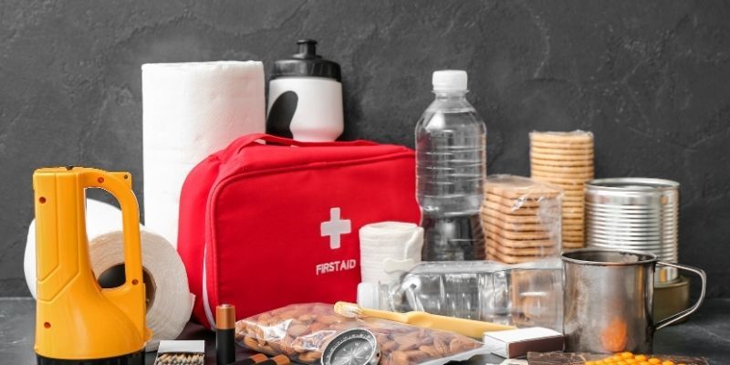 A red first aid kit placed on a table alongside various medical supplies and items.