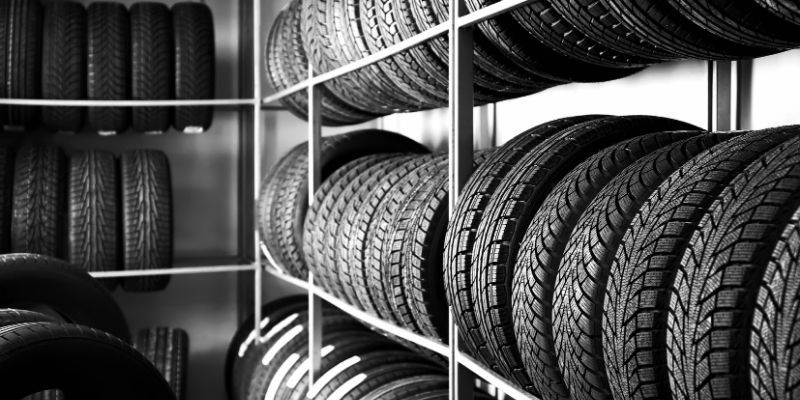 A black and white image showcasing neatly arranged tyres on shelves.