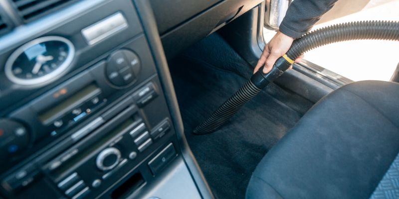 A person meticulously cleans the interior of a car, ensuring every detail is spotless and well-maintained.