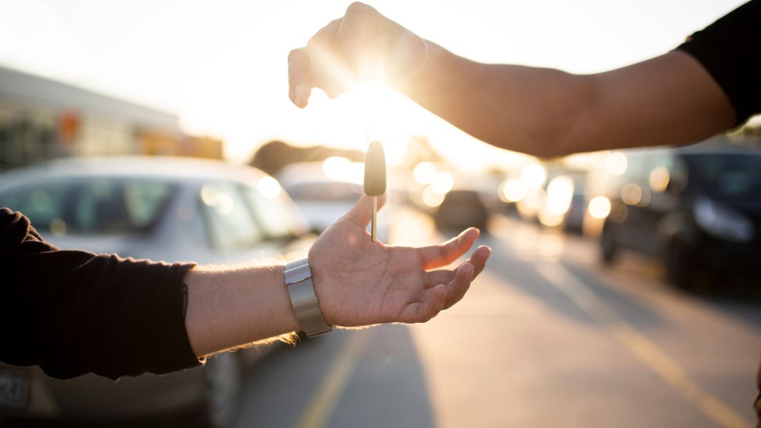 Handing over car keys, backlit by the sun.