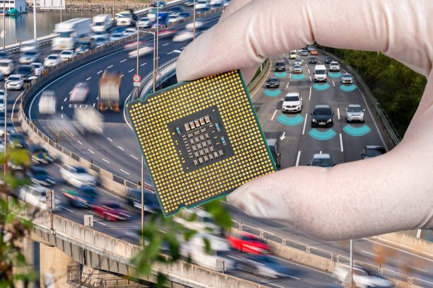 A busy motorway in the background. A hand holding a computer chip in the foreground.