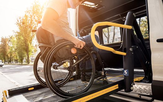 A male wheelchair user using a ramp to get into a car. 