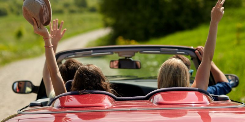A group of people in a convertible car in the sun