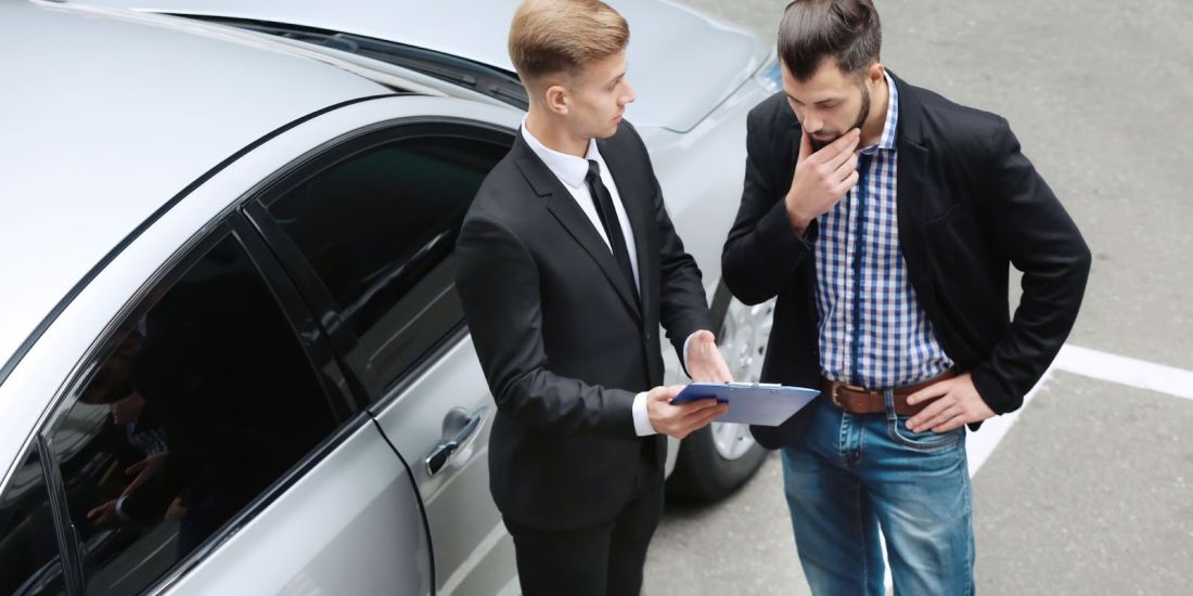 2 Gentlemen in Suits Outside A Car