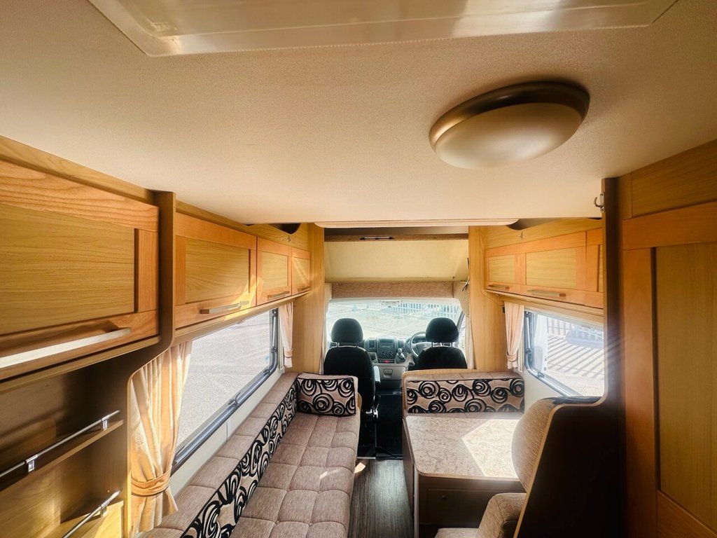 Inside a motor home, a sofa and a bed are arranged, highlighting the functional living area.