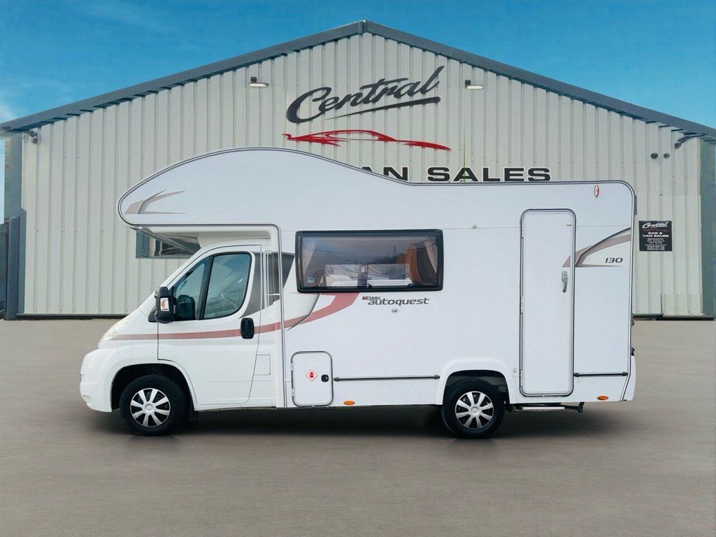 A white camper van is parked outside a building, highlighting its mobility in an urban setting.