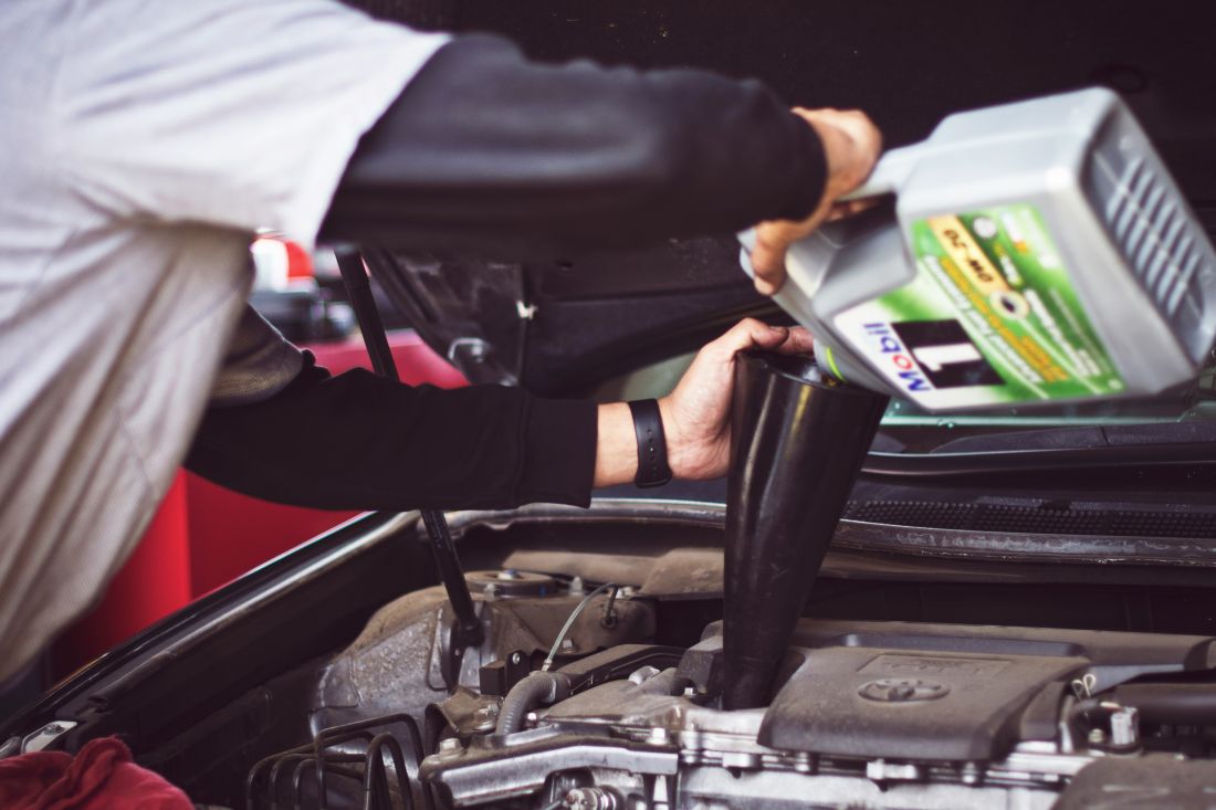 man putting oil in car 