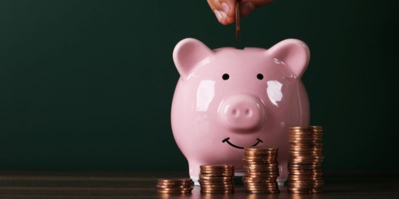 A piggy bank with a stack of coins in front, symbolising savings and financial security.