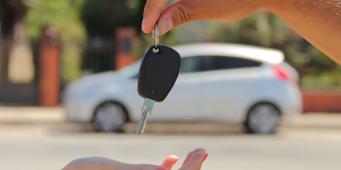 Car key being handed over, symbolizing successful sale of a car.