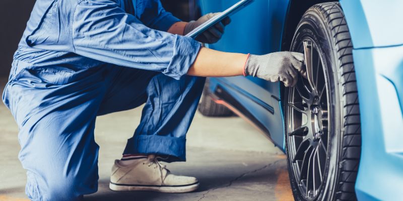A man inspecting a car wheel to ensure proper maintenance and repair.