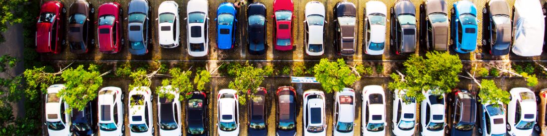 Aerial view of a car dealership lot filled with rows of parked vehicles.
