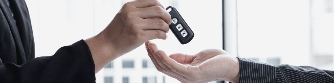 A close up of a car salesmans hands, passing a car buyer their keys.
