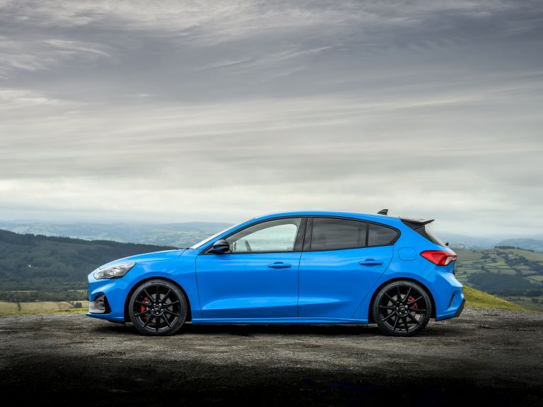 Blue Ford Focus hatchback parked on a hilltop road with scenic countryside views.