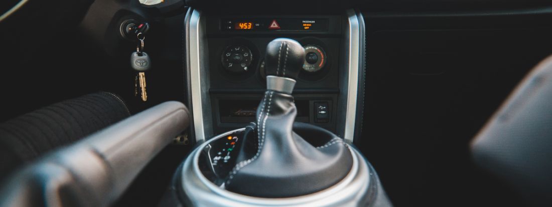 Close-up of a car interior with manual gear stick, handbrake and keys in the ignition.
