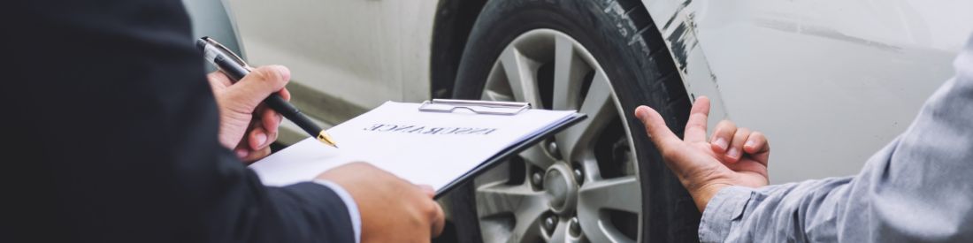 Insurance agent assessing car damage and writing insurance claim report after accident.