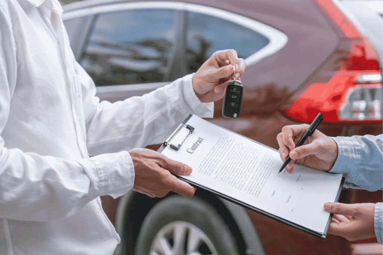 A man signing a car sales contract and collecting the car keys