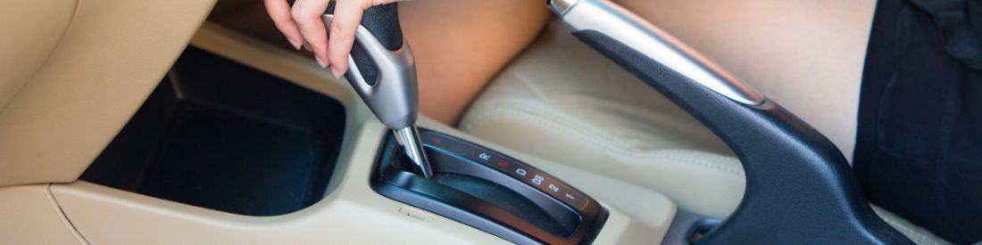 An automatic gear stick in a beige car interior.