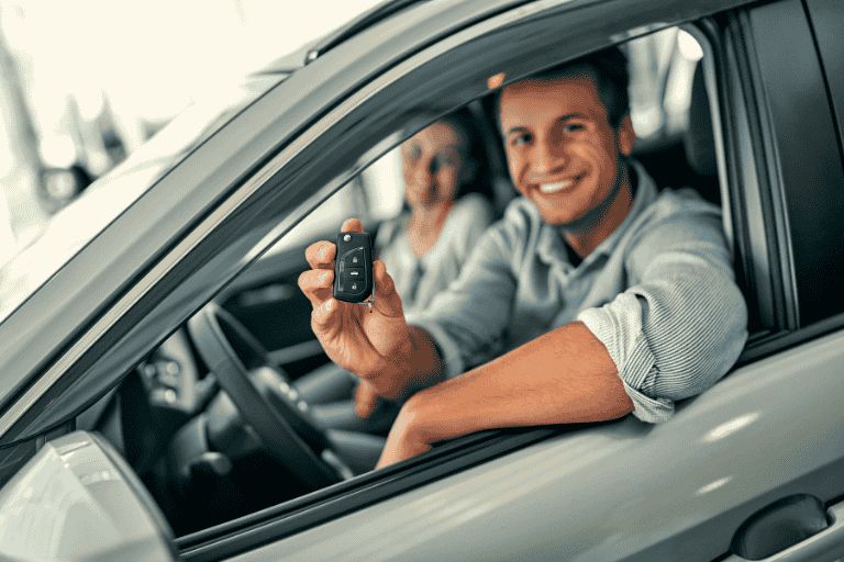 Happy customers, smiling in their new car holding the car keys.