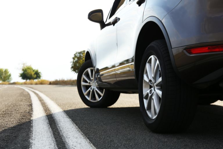 Close up image of a car's wheels on an open road.