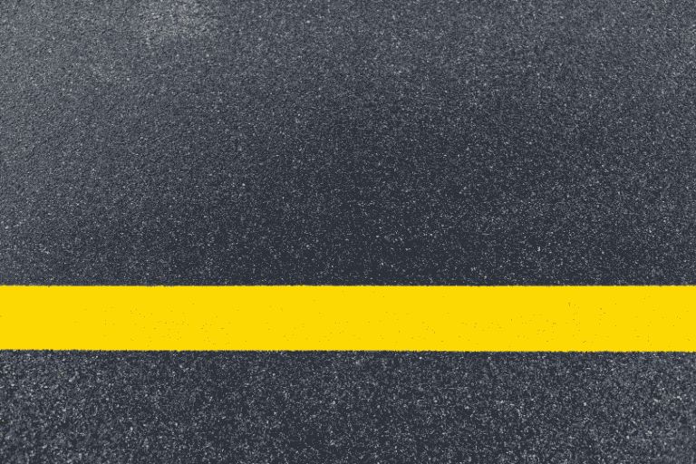 Single yellow line on a granite grey road.