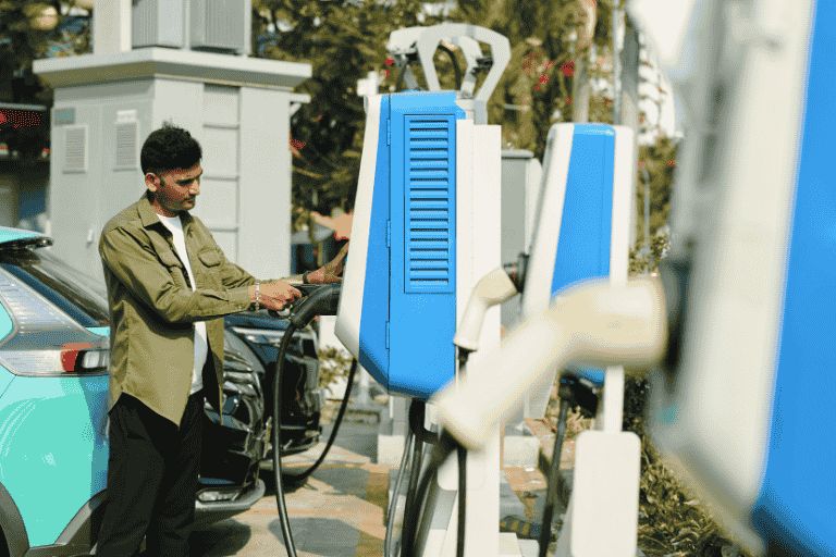 A man in a green shirt is charging his car at an EV charging point.
