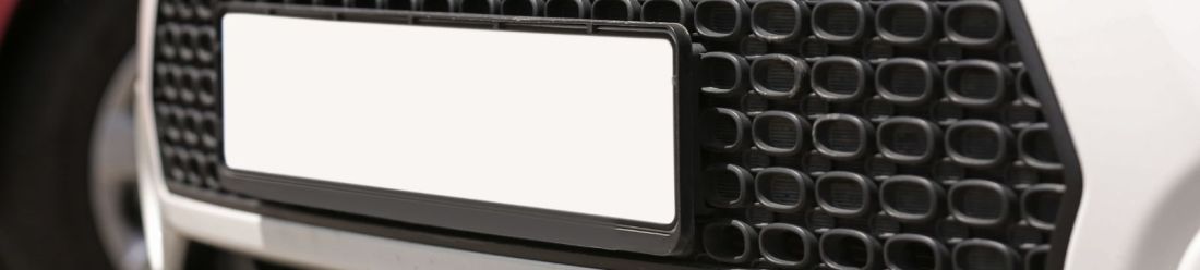 Up close image of a blank car number plate on a white car