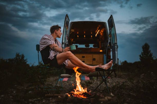 man sat outside campervan by campfire