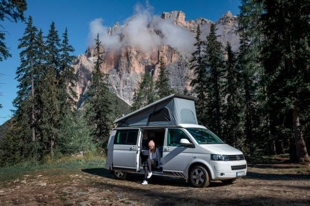 woman sat in Volkswagen camper with mountainous backdrop
