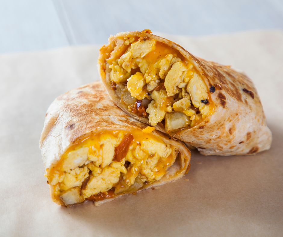 A breakfast burrito cut in half to show the different fillings. 