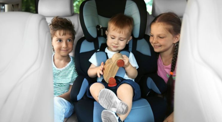 three children in the back seat of a car