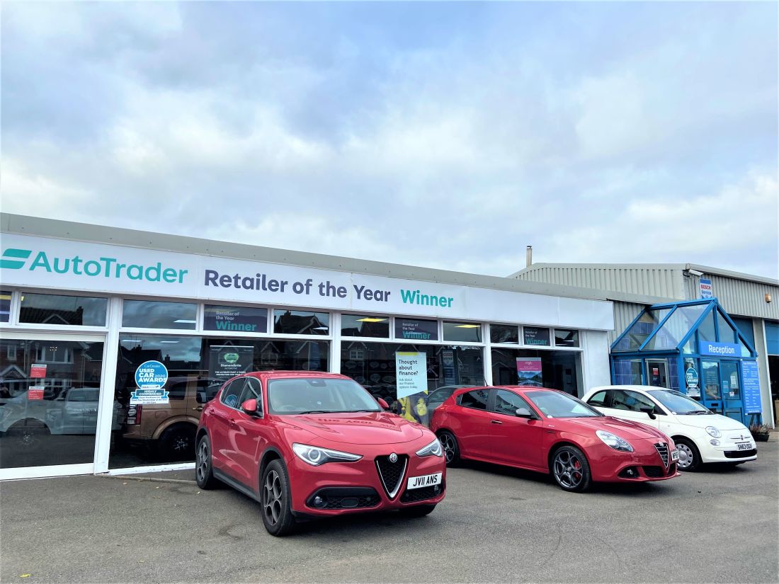A red MG, red Alfa Romeo and white Fiat are parked in front of Angus MacKinnon. 