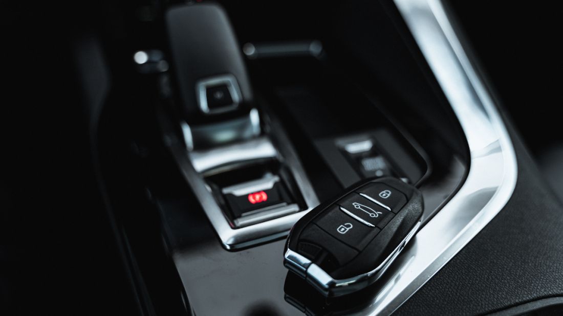 Close-up of a car's control panel featuring various buttons and a car key placed nearby.