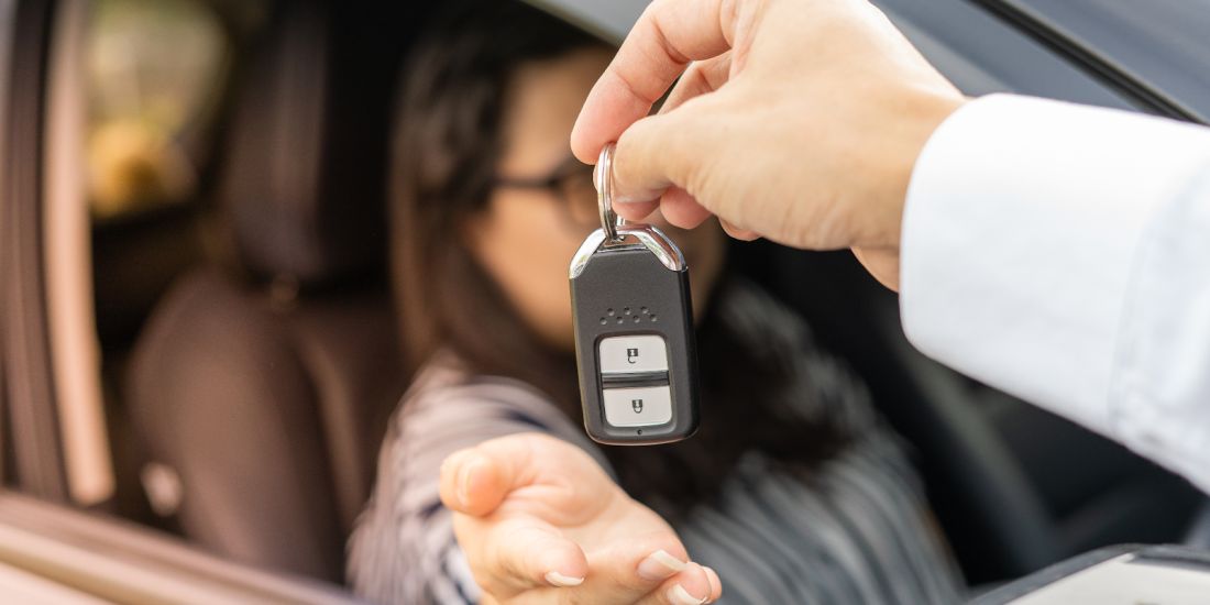 A person holding a car key in their hand, ready to unlock or start a vehicle.