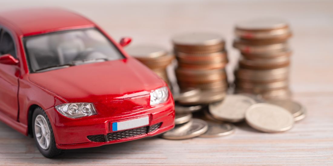 A red car rests on piles of coins
