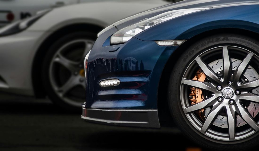 Close-up of a sports car's front wheel, showcasing its sleek design and intricate details.			 			