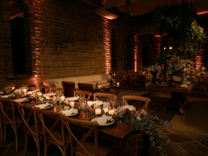 An elegant indoor Christmas reception featuring soft candlelight and lush greenery as decor.			 			
