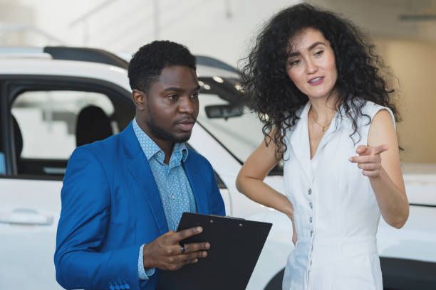 People standing in car showroom with clip board 