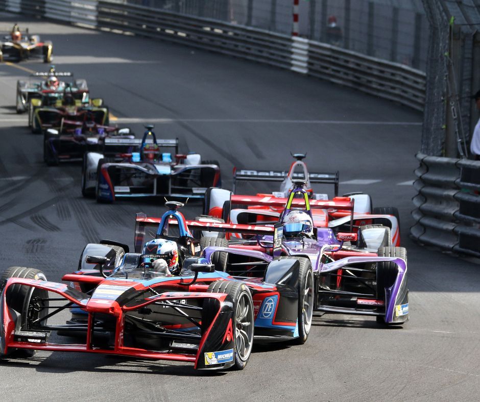 A group of F1 race cars speeding on the track.