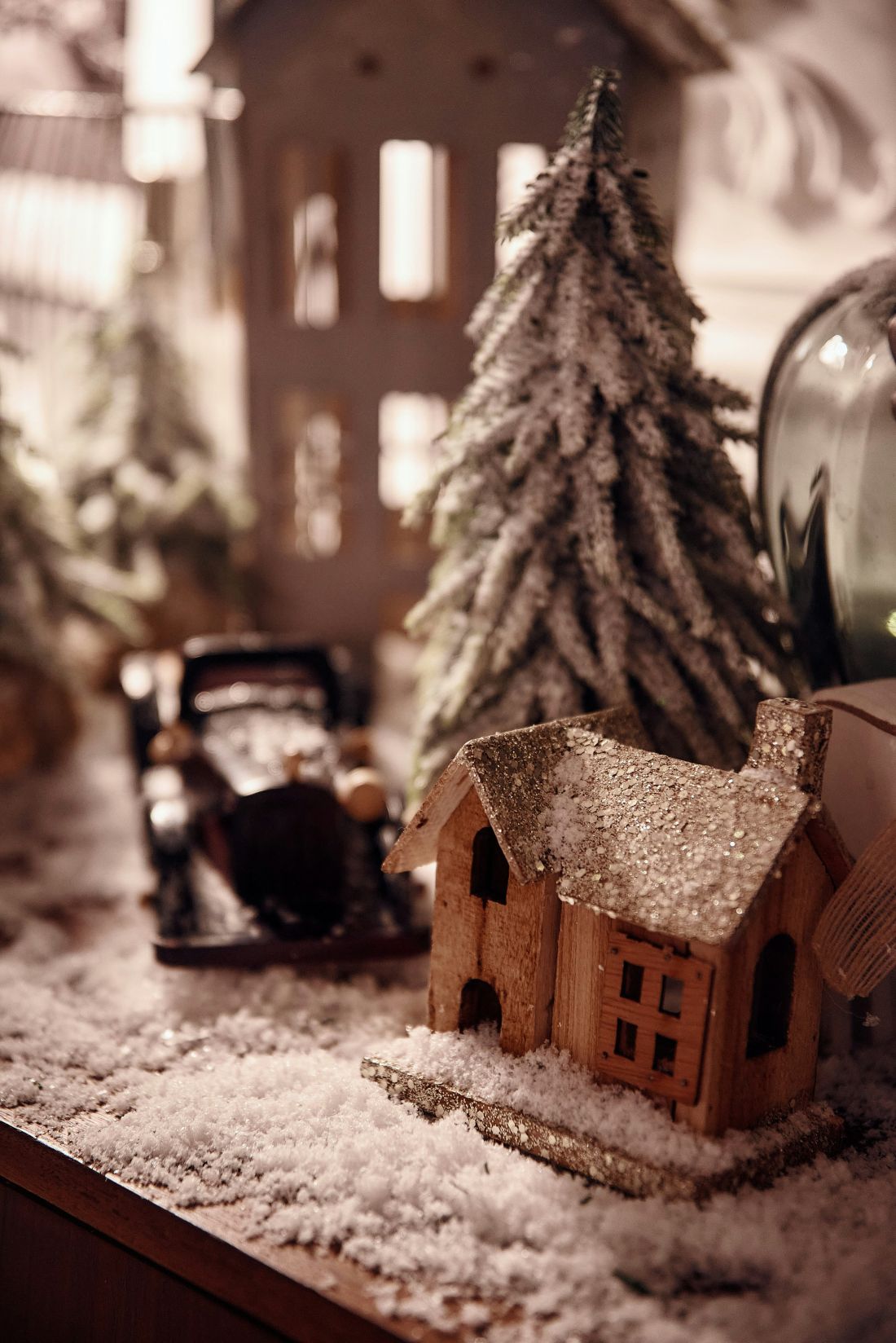 A small house and a decorated Christmas tree placed on a table, creating a festive holiday atmosphere.
