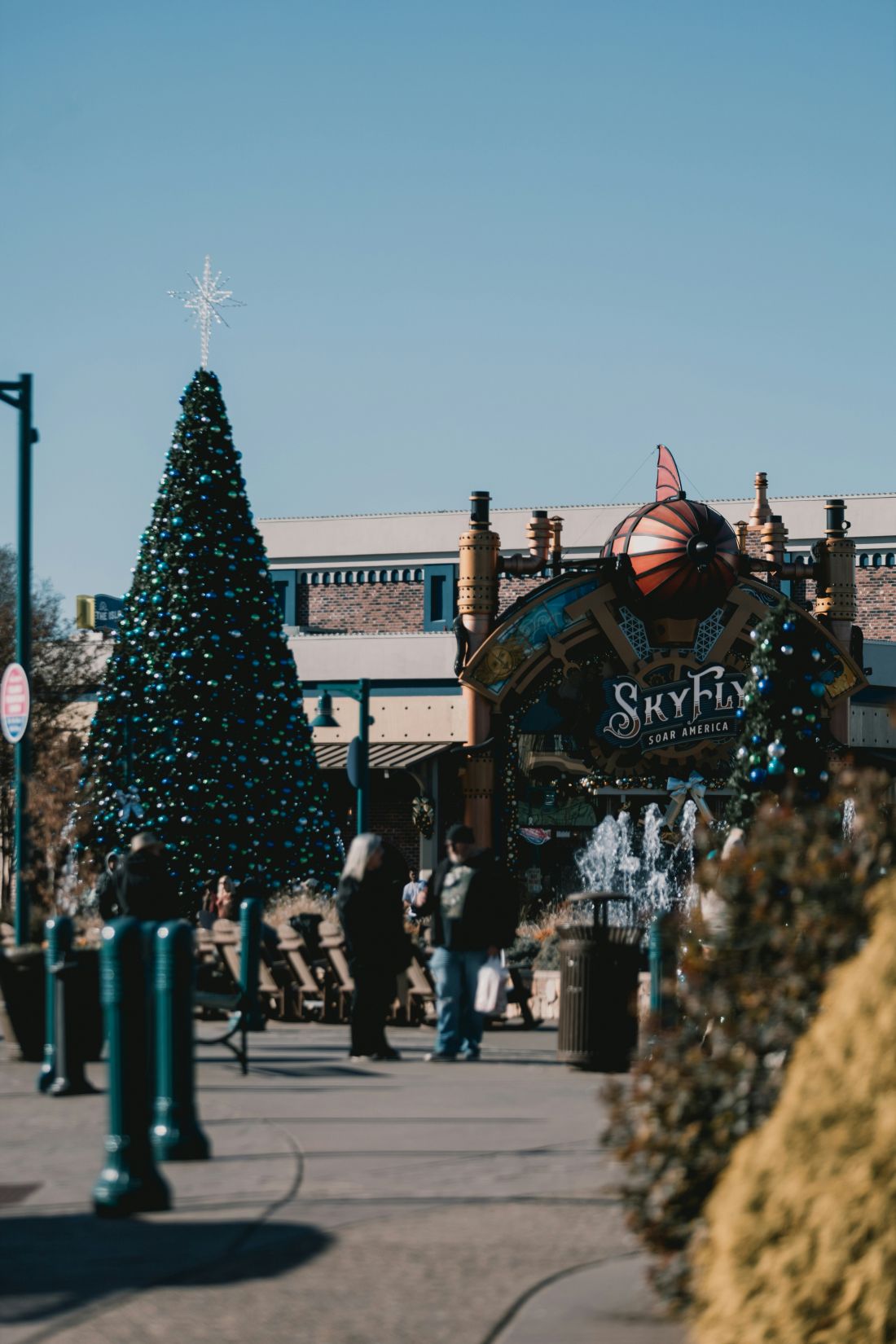 A festive Christmas tree, adorned with ornaments and lights, is prominently displayed in front of a store entrance.