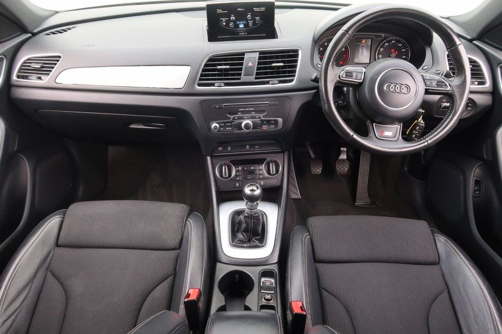 Interior view of an Audi Q3 car, showcasing sleek leather seats and modern dashboard features.