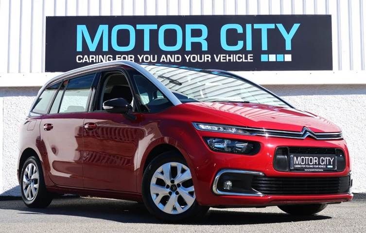A red Citroën parked in front of a Motor City sign, showcasing the vibrant urban landscape.