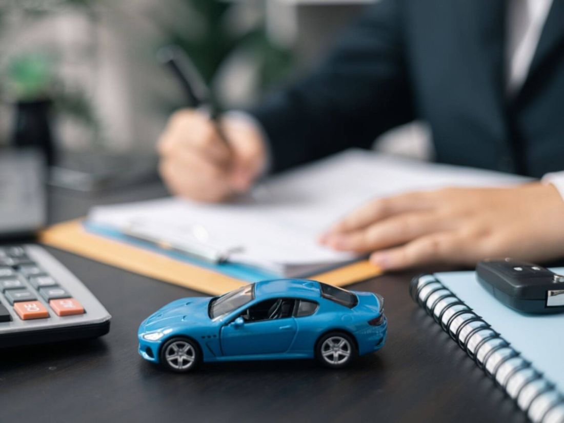 Man signing contract with a blue toy car in focus 