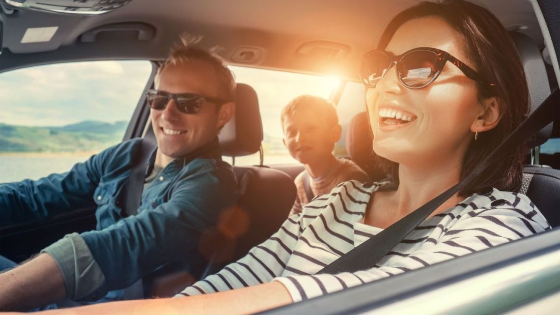Happy family enjoying a sunny drive in a modern car.