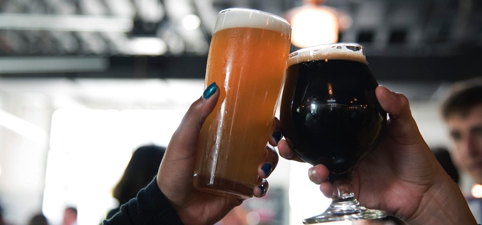 Two people clinking glasses of craft beer.