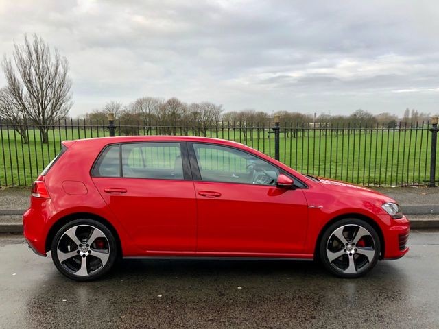 Red Volkswagen Golf, side profile, parked outdoors.